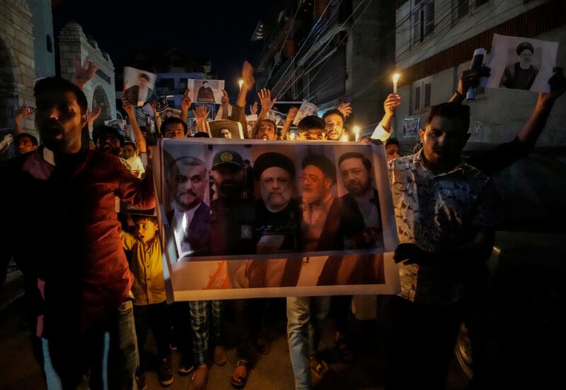 Shiite Muslims hold photos of Iranian President Ebrahim Raisi (Mukhtar Khan/AP)