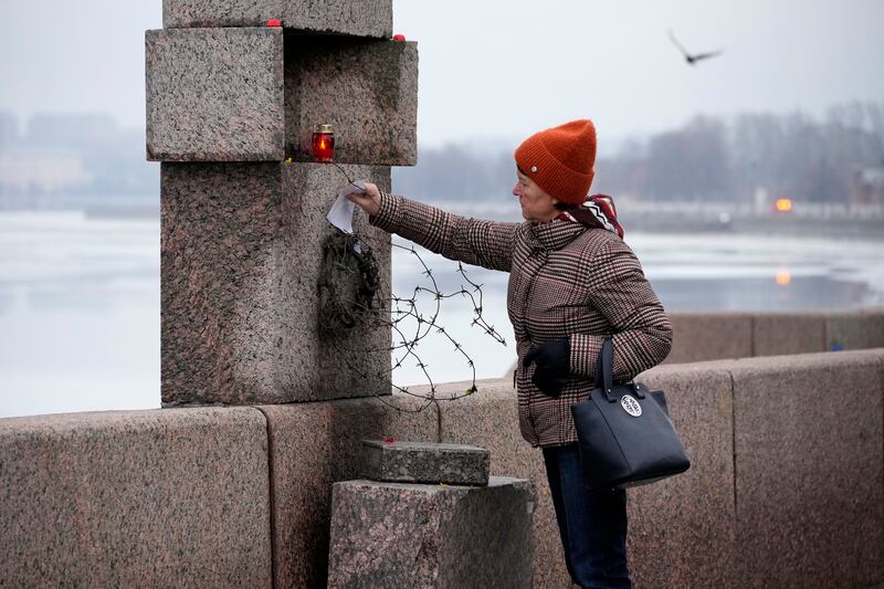 A woman places a piece of paper with words of grief for Alexei Navalny at the Memorial to Victims of Political Repression in St Petersburg, Russia (Dmitri Lovetsky/AP)