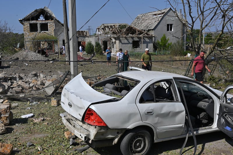 People walk in front of their damaged houses after Russian rocket attack in Usatove village near Odesa