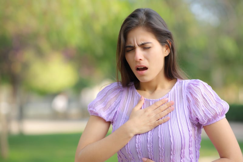 Stressed woman suffering from an asthma attack in a park