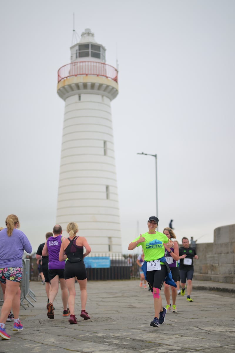 Group of runners in 5k race in front of white lighthouse