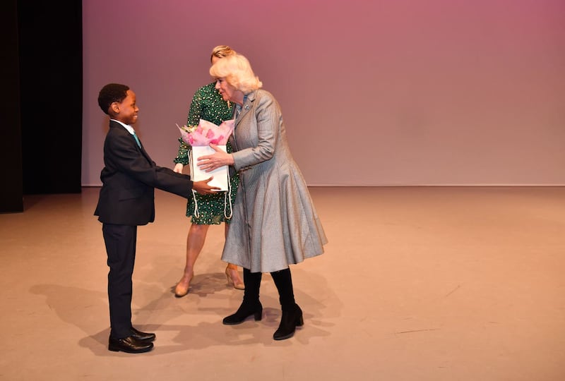 The Duchess of Cornwall receives a bouquet of flowers from a pupil on stage during a visit to Elmhurst Ballet School in Birmingham