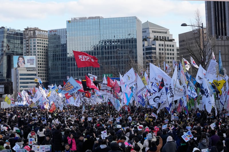 Protesters carry flags during a rally demanding the immediate indictment of impeached South Korean President Yoon Suk Yeol in Seoul (Ahn Young-joon/AP)