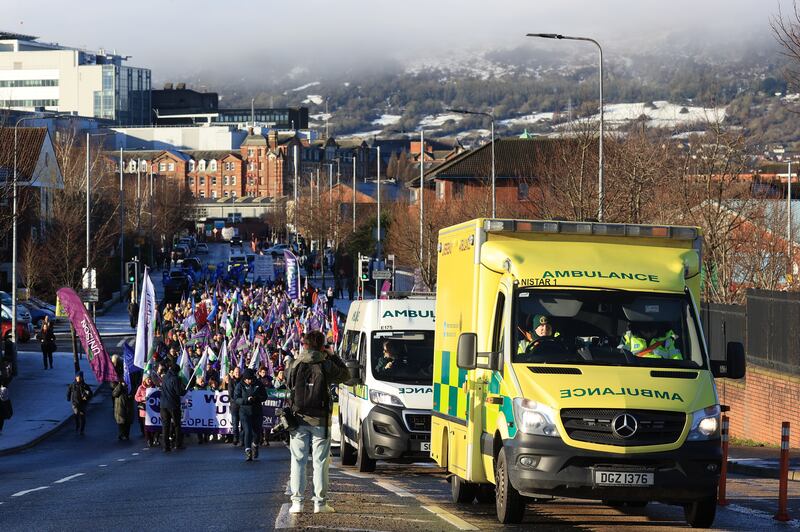 Ambulances drive ahead of a parade of public sector workers from the Unison union along with other public sector workers. The strikers are walking from the picket line at the Royal Victoria Hospital to Belfast City Hall carrying placards and banners and are wrapped up warmly in winter clothing