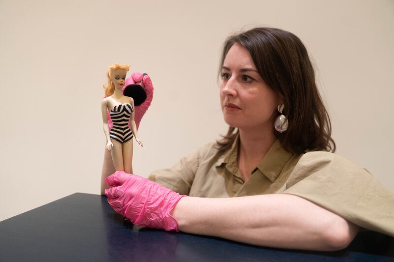 Exhibition curator Danielle Thom holds a rare first edition Barbie doll