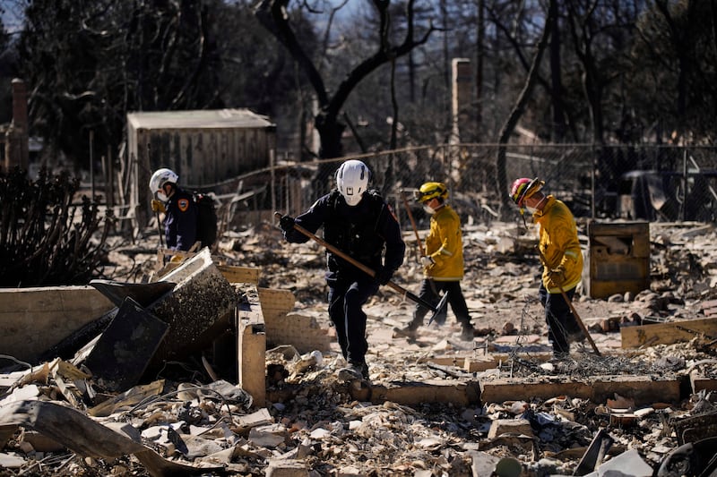 A search and rescue crew sifts through the wreckage of a home destroyed by the Eaton Fire in Altadena (John Locher/AP)