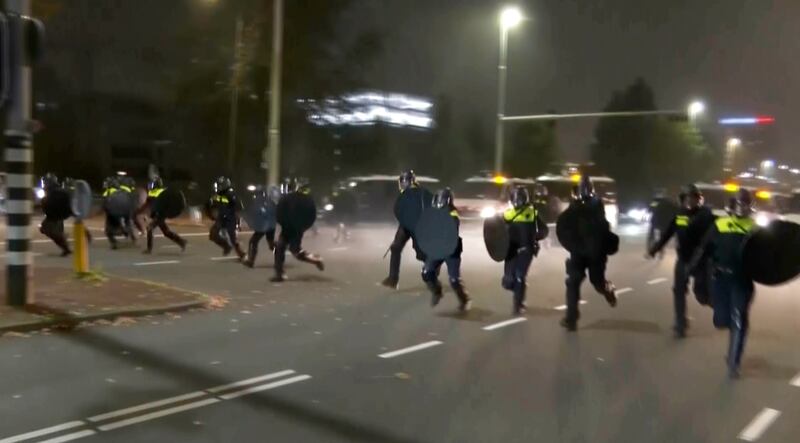 Police in riot gear run towards protesters, after pro-Palestinian supporters marched near the football stadium, in Amsterdam, Netherlands (RTL Nieuws via AP)