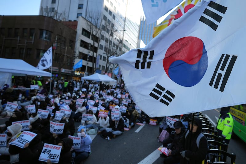 Participants hold signs during a rally calling on the Constitutional Court to dismiss President Yoon Suk Yeol in Seoul on Sunday. The signs read “Immediately arrest.” (Lee Jin-man/AP)