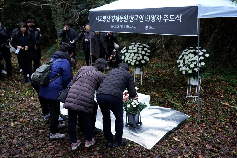 Relatives of Korean victims and South Korean officials offer flowers (Eugene Hoshiko/AP)