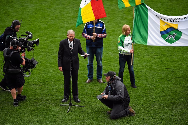 Micheal O Muircheartaigh speaking during the Laochra entertainment performance after the Allianz Football League Final with TV cameras and club flags in the background