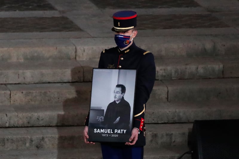 A Republican Guard holds a portrait of Samuel Paty in the courtyard of the Sorbonne university during a national memorial event in 2020 in Paris (Francois Mori/AP)