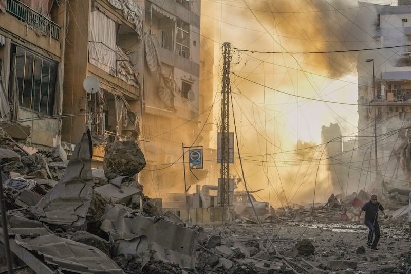 A man runs for cover as smoke rises in the background following an Israeli air strike in Dahiyeh, Beirut, Lebanon (Hassan Ammar/AP)