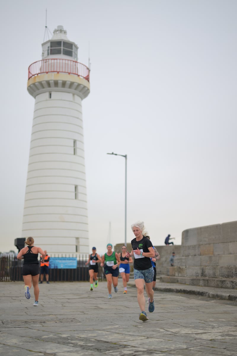 Group of runners in 5k race in front of white lighthouse